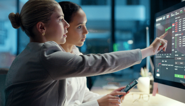 Two women looking at a screen with a graph and data