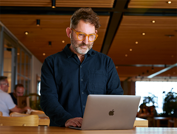 Ein Apple Corporate Teammitglied arbeitet in einem Caffè Macs an einem MacBook.