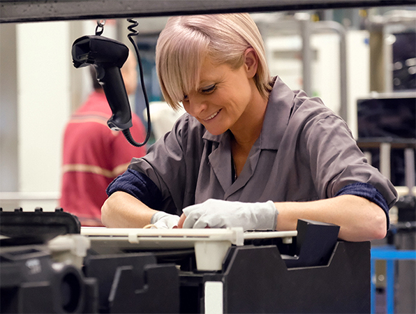 Zwei Apple Teammitglieder prüfen Mac Aluminiumgehäuse in einer Apple Fertigungsstraße zum Anodisieren von Titan.