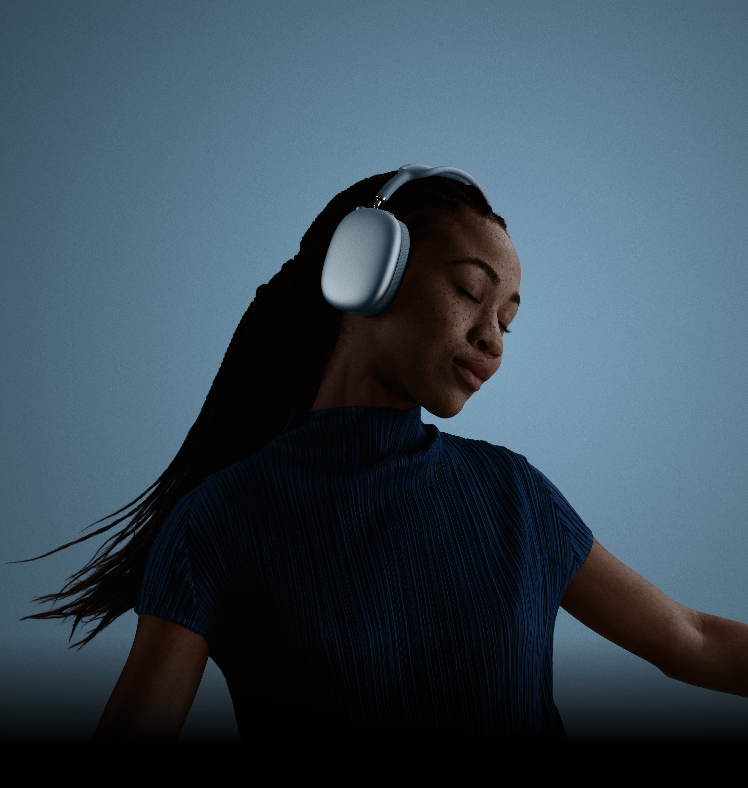 Une femme avec les yeux fermĂ©s, la tĂȘte penchĂ©e vers la gauche, portant des AirPods Max.