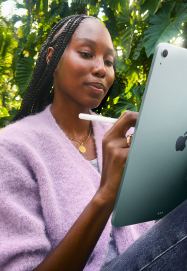 Een student zit buiten. Ze houdt een iPad en een Apple Pencil Pro vast.