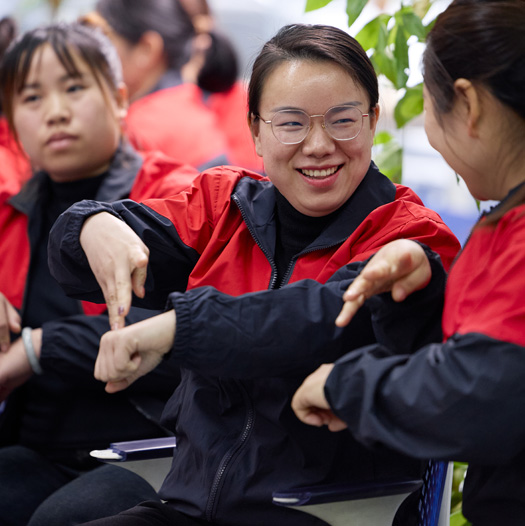 三名員工坐在一起，其中一位向另一位比手語 