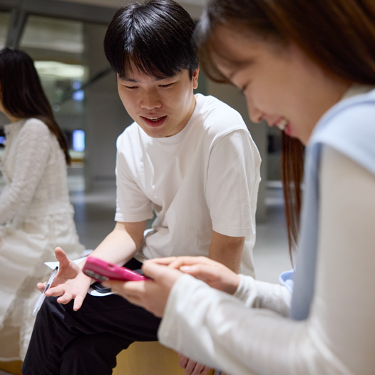 兩個人邊交談邊低頭看著 iPhone，其中一人拿著 iPhone 在瀏覽