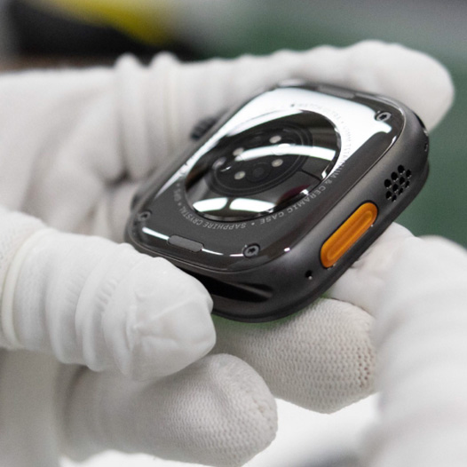 戴著手套的雙手拿著底部朝上的 Apple Watch