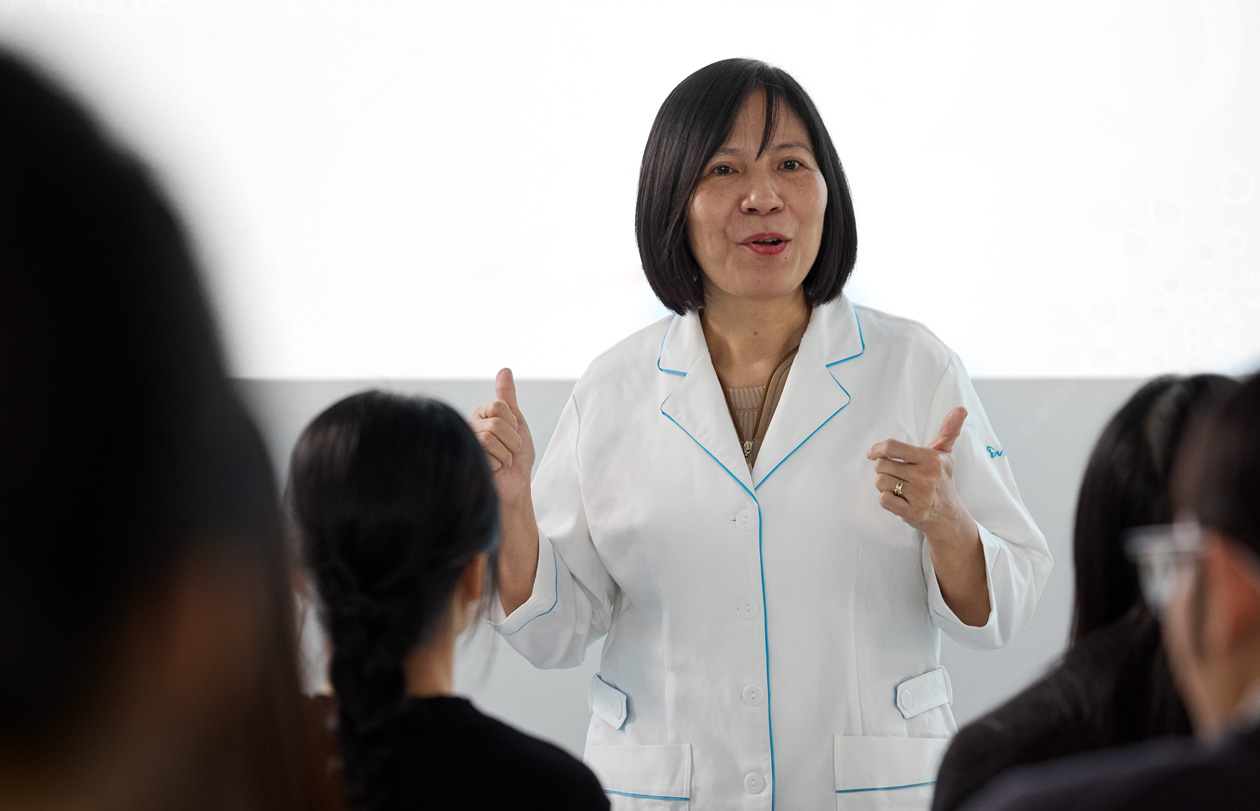 一名身穿白色實驗室外套的講師在坐滿學生的教室前面授課
