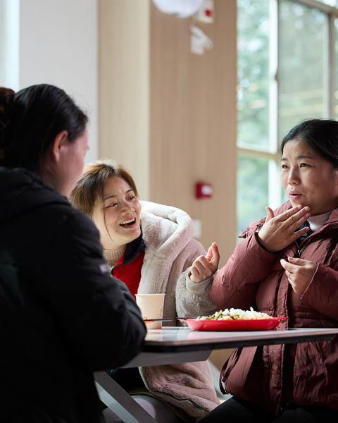 三個人坐在餐廳的桌子旁，用手語互相交流