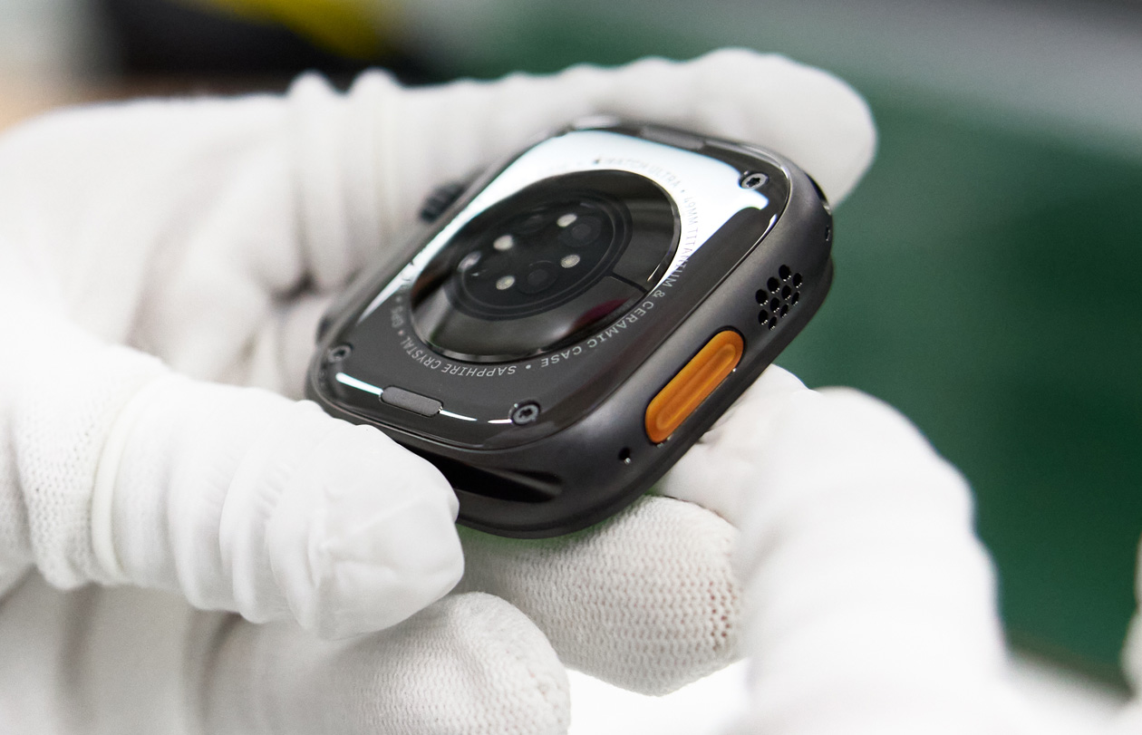 戴著手套的雙手拿著底部朝上的 Apple Watch