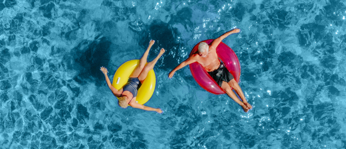 Man and woman floating on colorful innertubes in a pool Man and woman floating on colorful innertubes in a pool